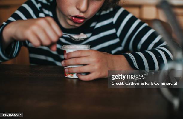 boy eating yogurt - yogurt spoon stock-fotos und bilder