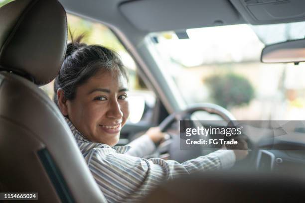 latin woman sitting in driver's seat, driving car - taxi driver stock pictures, royalty-free photos & images