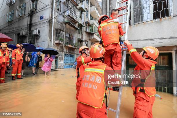 Rescuers evacuate a child from a building in a flooded area after heavy rain in Hengyang in central China's Hunan province on July 9, 2019. / China...