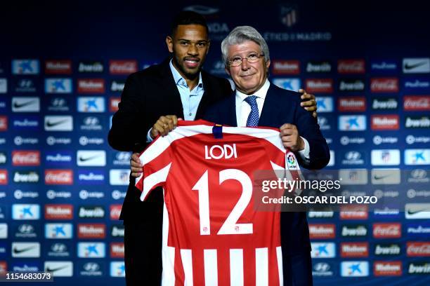 Atletico Madrid's new Brazilian defender Renan Lodi holds his new jersey next to the Spanish football club's president Enrique Cerezo during his...