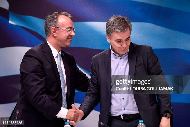 Newly appointed Finance Minister Christos Staikouras shakes hands with outgoing Finance Minister Euclid Tsakalotos during a ceremony at the ministry...