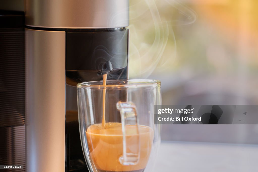 Coffee maker pouring into glass mug