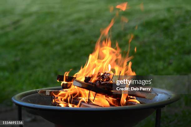 close up view of a fire pit (fire ring) burning wood on a patio - ring flames stock-fotos und bilder