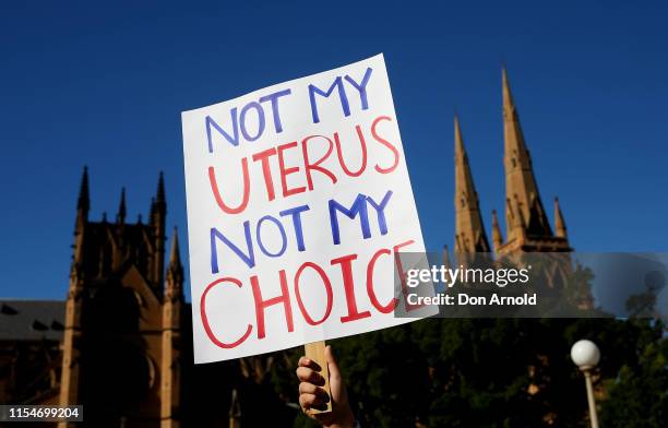 Man holds up signage against the backdrop of St Mary's Cathedral in Hyde Park on June 09, 2019 in Sydney, Australia. The march was organised by a...
