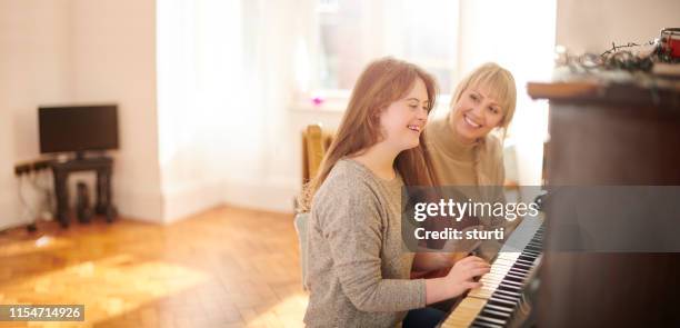 mother and daughter playing piano - down syndrome girl stock pictures, royalty-free photos & images