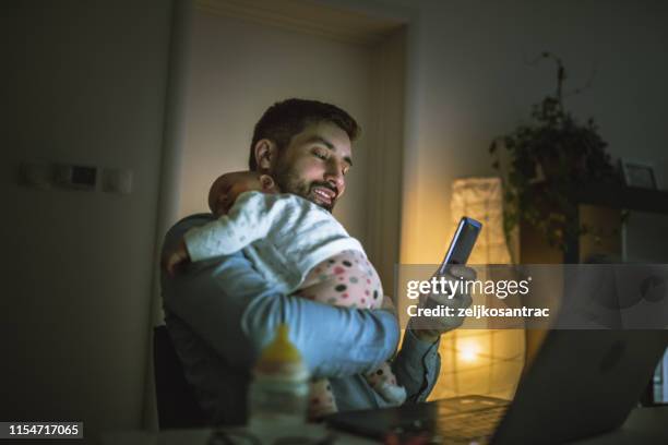 junger vater arbeitet zu hause mit seinem baby mädchen - familie laptop stock-fotos und bilder