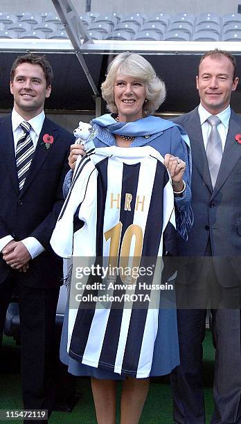 Camilla Duchess of Cornwall is presented with a Newcastle United shirt and poses with Michael Owen and Alan Shearer during a visit to Newcastle...