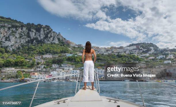 woman on  a boat watching mediterranean village - capri pants photos et images de collection