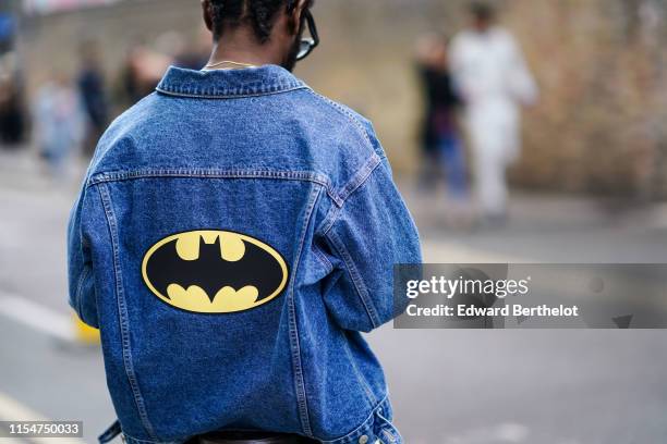 Guest wears a blue denim jacket with a printed Batman logo, during London Fashion Week Men's June 2019 on June 08, 2019 in London, England.