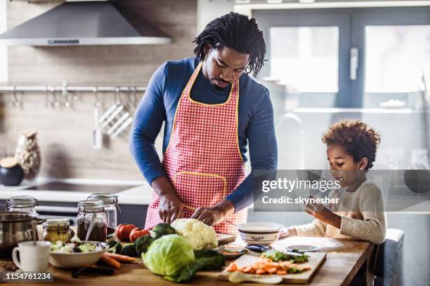 schwarzer vater und tochter bereiten gesundes mittagessen in der küche vor. - black cook stock-fotos und bilder