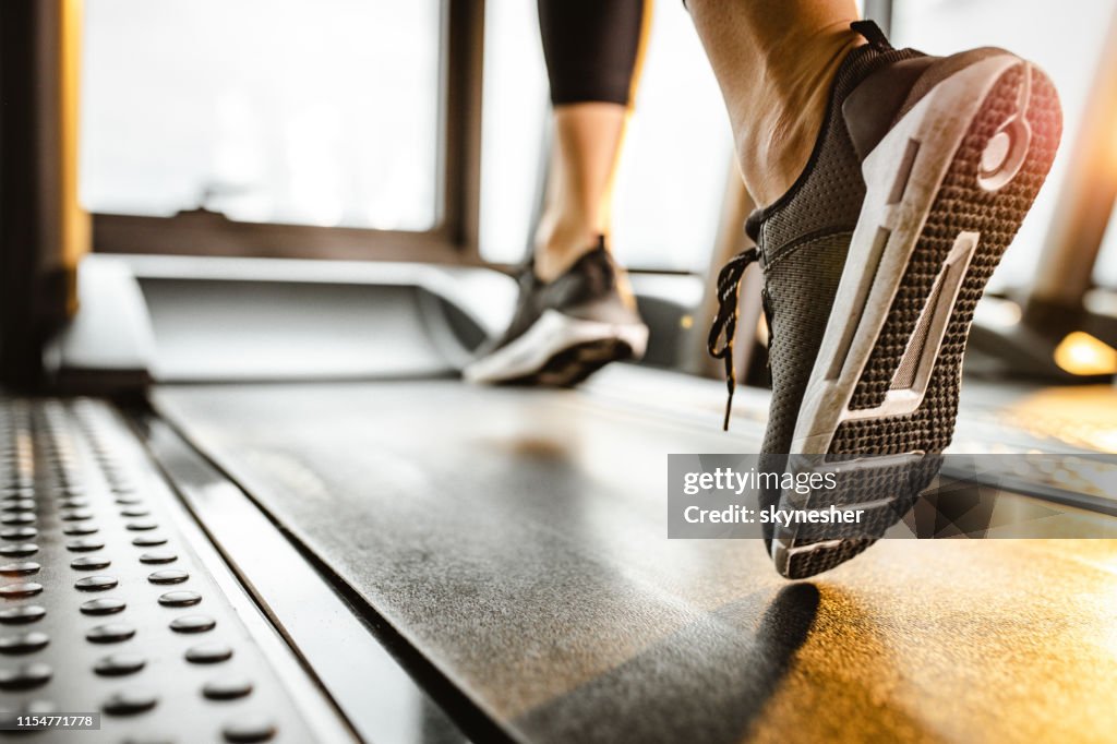 Close up of unrecognizable athlete running on a treadmill in a gym.