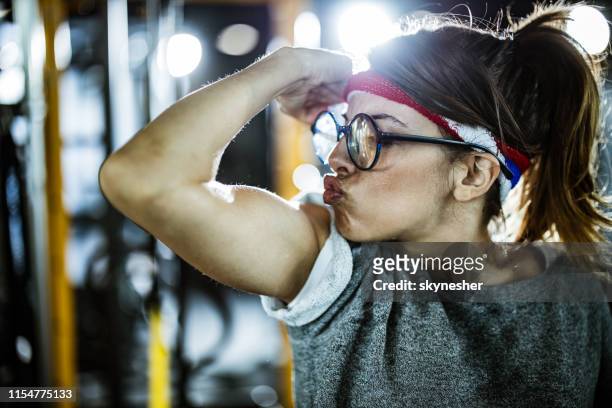 nerdy athletische frau, die ihre bizeps in einem fitnessstudio. - selbstverliebt stock-fotos und bilder