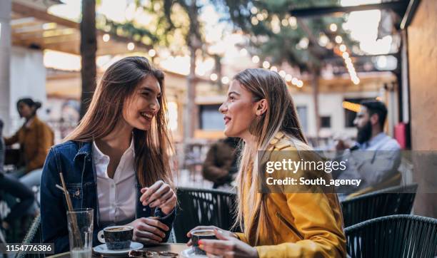 belle donne che bevono caffè in un giardino del caffè - bar people foto e immagini stock