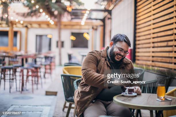 hombre barbudo bebiendo café en un jardín de café - hombre gordo fotografías e imágenes de stock