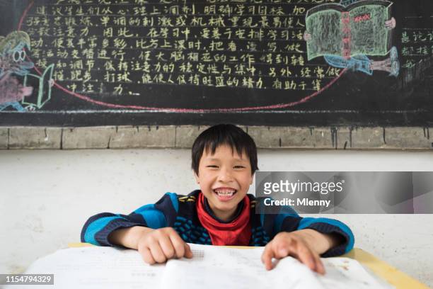 chinese jongen met plezier op docenten bureau in de chinese schoolklas lokaal - chinese teenage boy stockfoto's en -beelden