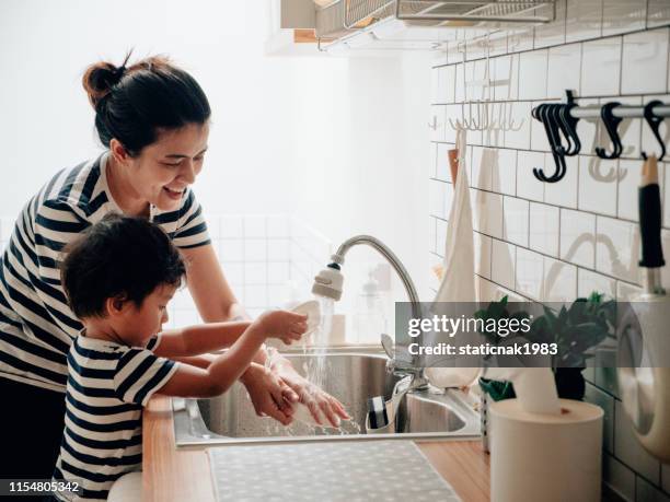 kleine baby jongen af te vegen schone gerechten met zijn moeder. - child washing hands stockfoto's en -beelden