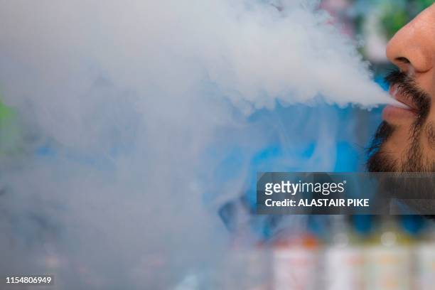 Man smokes an electronic cigarette inside a vape shop in Washington, DC, on July 9, 2019.