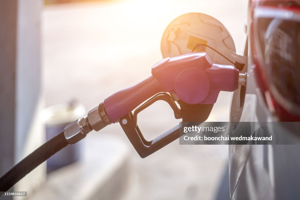 Fuel oil gasoline dispenser at petrol filling station.Holding fuel nozzle to refuel gasoline for car.