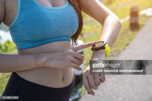 close up image of young woman checking the time on smartwatch device after jog, outdoors. - arm span stockfoto's en -beelden