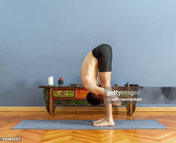 man doing uttanasana pose in yoga - man bending forward stock pictures, royalty-free photos & images