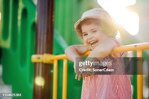 Little Cute Girl With Hat Playing At Playground Outdoors In Summer Little Cute Girl With Hat Playing At Playground Outdoors In Summer