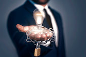A man holding light bulb, lock and chain. Patented Idea Concept. All rights reserved