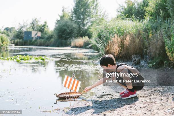 boy with toy boat at pond - testing the water engelse uitdrukking stockfoto's en -beelden