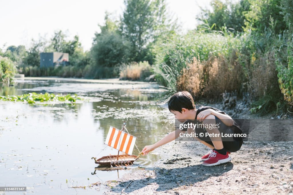 Boy with toy boat at pond