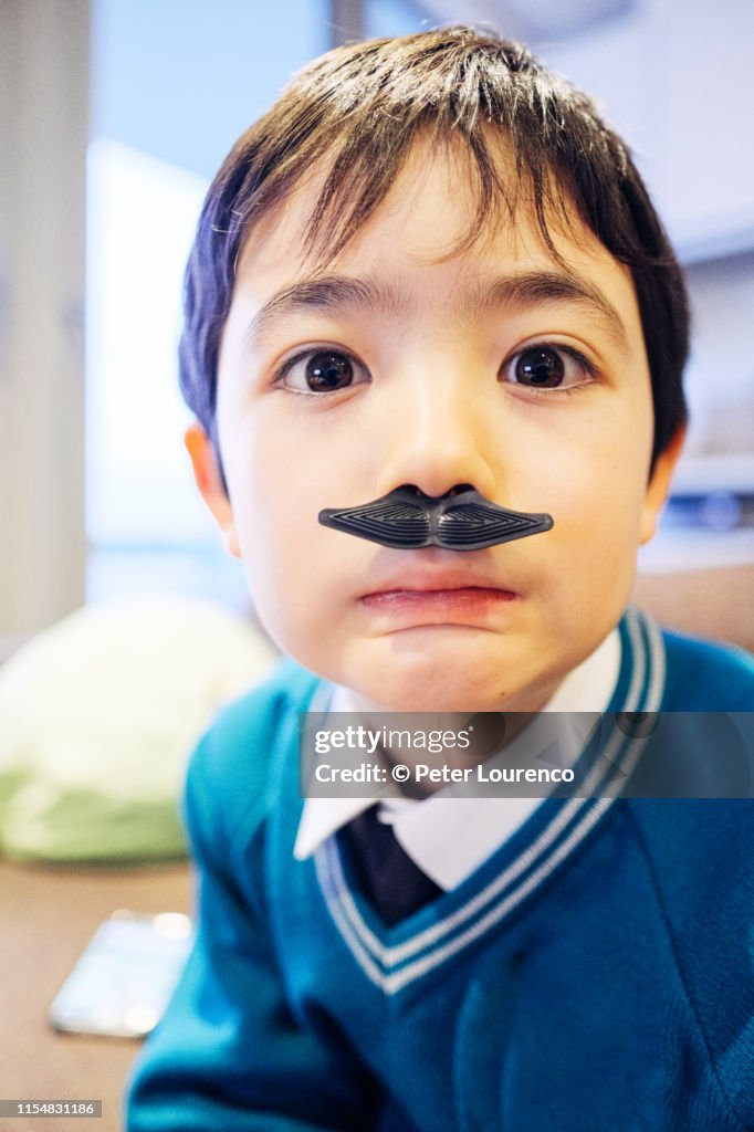 Boy wearing plastic moustache