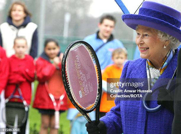 Queen Elizabeth II holds a tennis racquet signed by the British Davis Cup team which was presented to her during her visit to the new National Tennis...