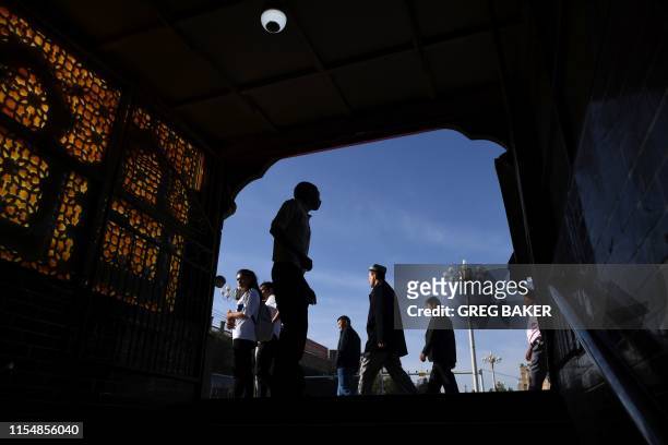 This photo taken on June 5, 2019 shows Uighur men walking past the exit of an underpass after attending Eid al-Fitr prayers, marking the end of...