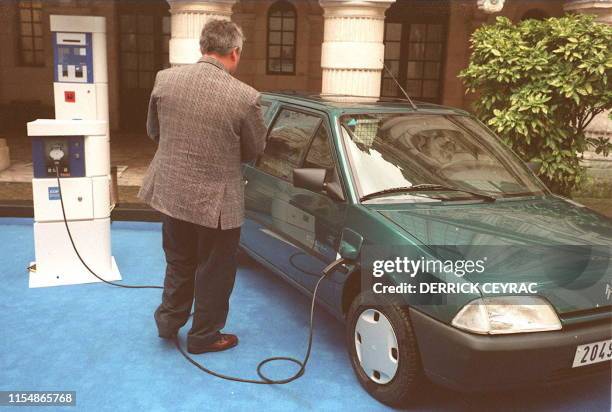 Photo prise le 13 décembre 1993 à La Rochelle d'un utilisateur de voiture électrique attendant la fin du "plein d'énergie" d'une Citroën AX...