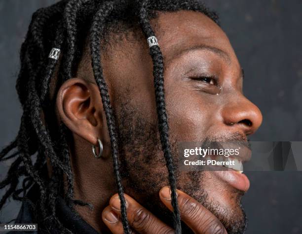 der junge westafrikanische mann mit der hand ins gesicht zeigt seine emotionen ... tränen der freude. - tears of joy stock-fotos und bilder