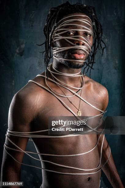 west african man experiments with decoration of the body using cable. - african refugee stock pictures, royalty-free photos & images