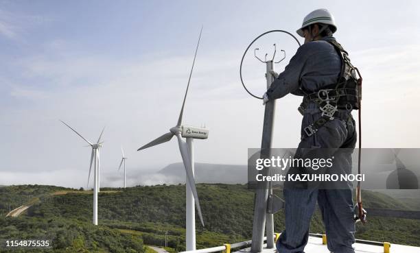 Japan-environment-climate-warming, by Patrice Novotny Ryo Nagasawa, chief mechanic of wind-power farm Eurus Energy Japan Corporation works on top of...