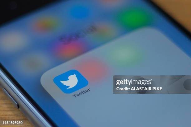 The Twitter logo is seen on a phone in this photo illustration in Washington, DC, on July 10, 2019. - Twitter is moving to filter out inappropriate...