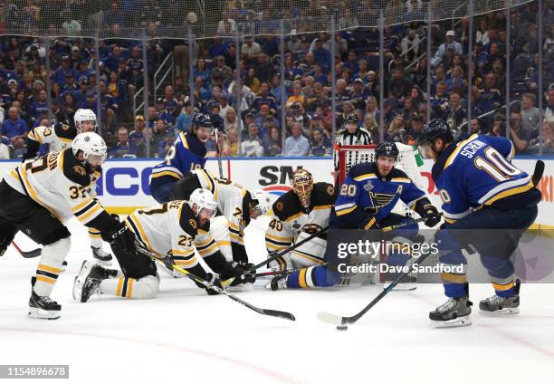 Brayden Schenn of the St. Louis Blues controls the puck as goaltender Tuukka Rask of the Boston Bruins and his teammates defend the play during the...