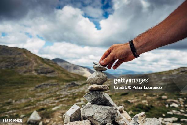 placing stone on cairn - steinpyramide stock-fotos und bilder