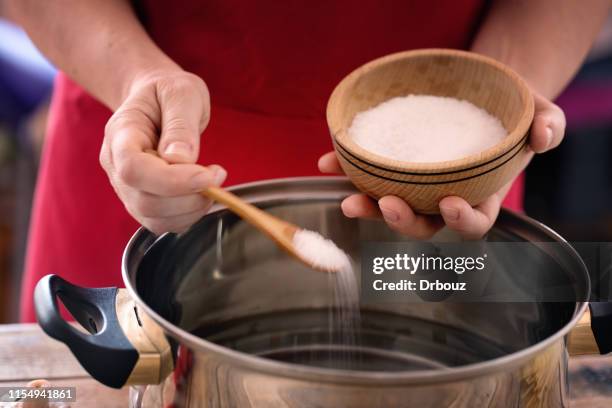 pasta-kochen-küchenchef legt meersalz in kochenden topf, aus der nähe - salt mineral stock-fotos und bilder