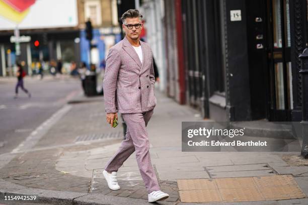 Eric Rutherford wears a pale purple blazer jacket, pants, white sneakers shoes, glasses, during London Fashion Week Men's June 2019 on June 09, 2019...