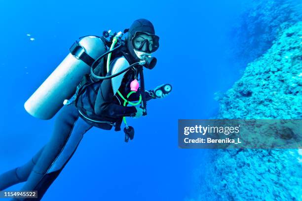 female scuba diver checking oxygen reserve and  diving depth. - aqualung diving equipment stock pictures, royalty-free photos & images