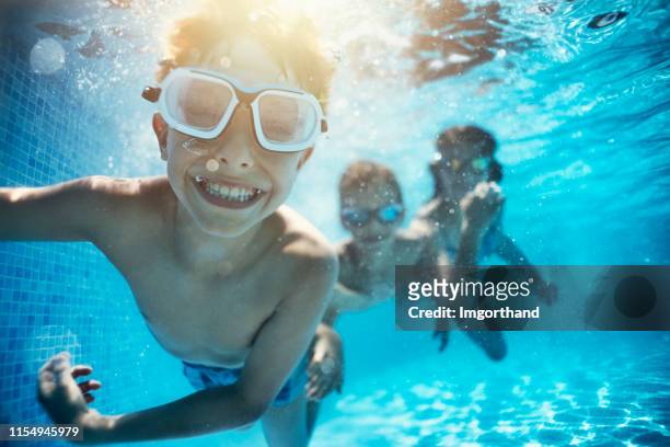 los niños jugando bajo el agua en la piscina - natación fotografías e imágenes de stock
