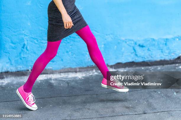 vrouw met rok en roze panty lopen op straat - paarse schoen stockfoto's en -beelden