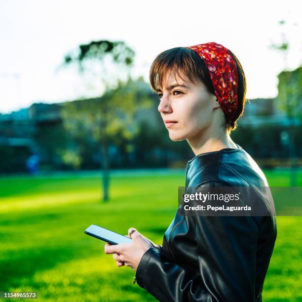 el uso del teléfono en un parque - cinta de cabeza fotografías e imágenes de stock
