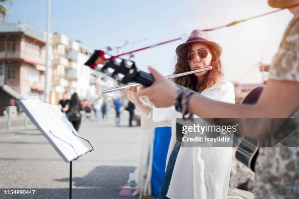 flutist and her guitarist friend are playing on the street - street musician stock pictures, royalty-free photos & images