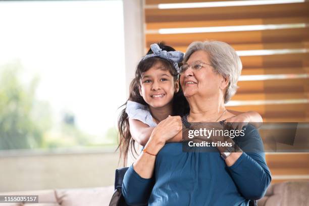 girl embracing grandmother at home - indian grandmother stock pictures, royalty-free photos & images