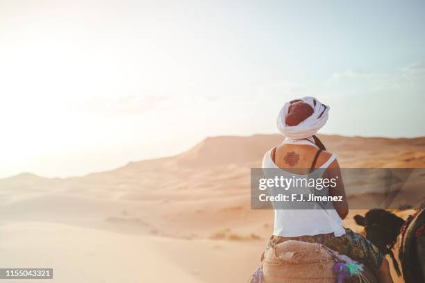 woman riding a camel in the desert of merzouga - midelt photos et images de collection