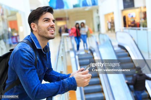 jonge man witn smart phone in mall - shopping screen stockfoto's en -beelden