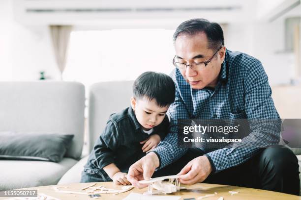 nonno che fa giocattolo aereo per il nipote carino - asian grandparents foto e immagini stock