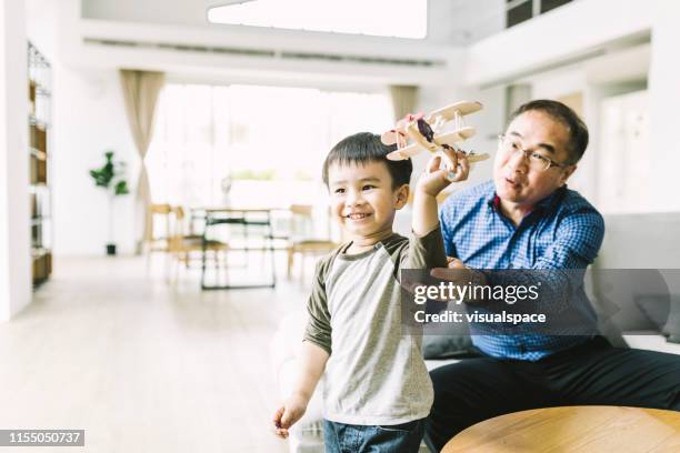 uomo che guarda il nipote che gioca con l'aereo giocattolo - asian grandparents foto e immagini stock